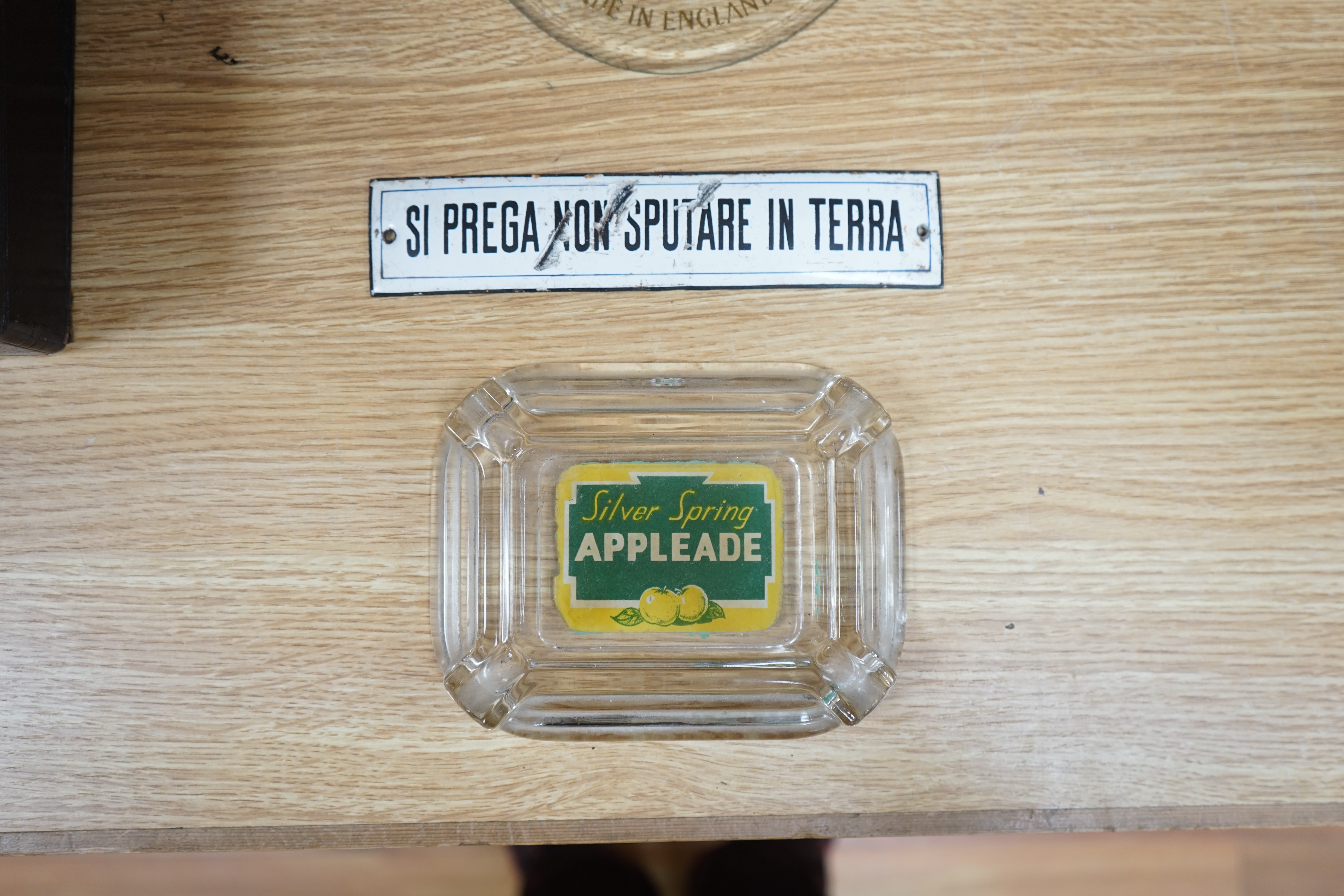 An early 20th century Lindt chocolate glass advertising sign, an enamel sign and an ‘Appleade’ glass ashtray, largest 41cm high. Condition - poor to fair